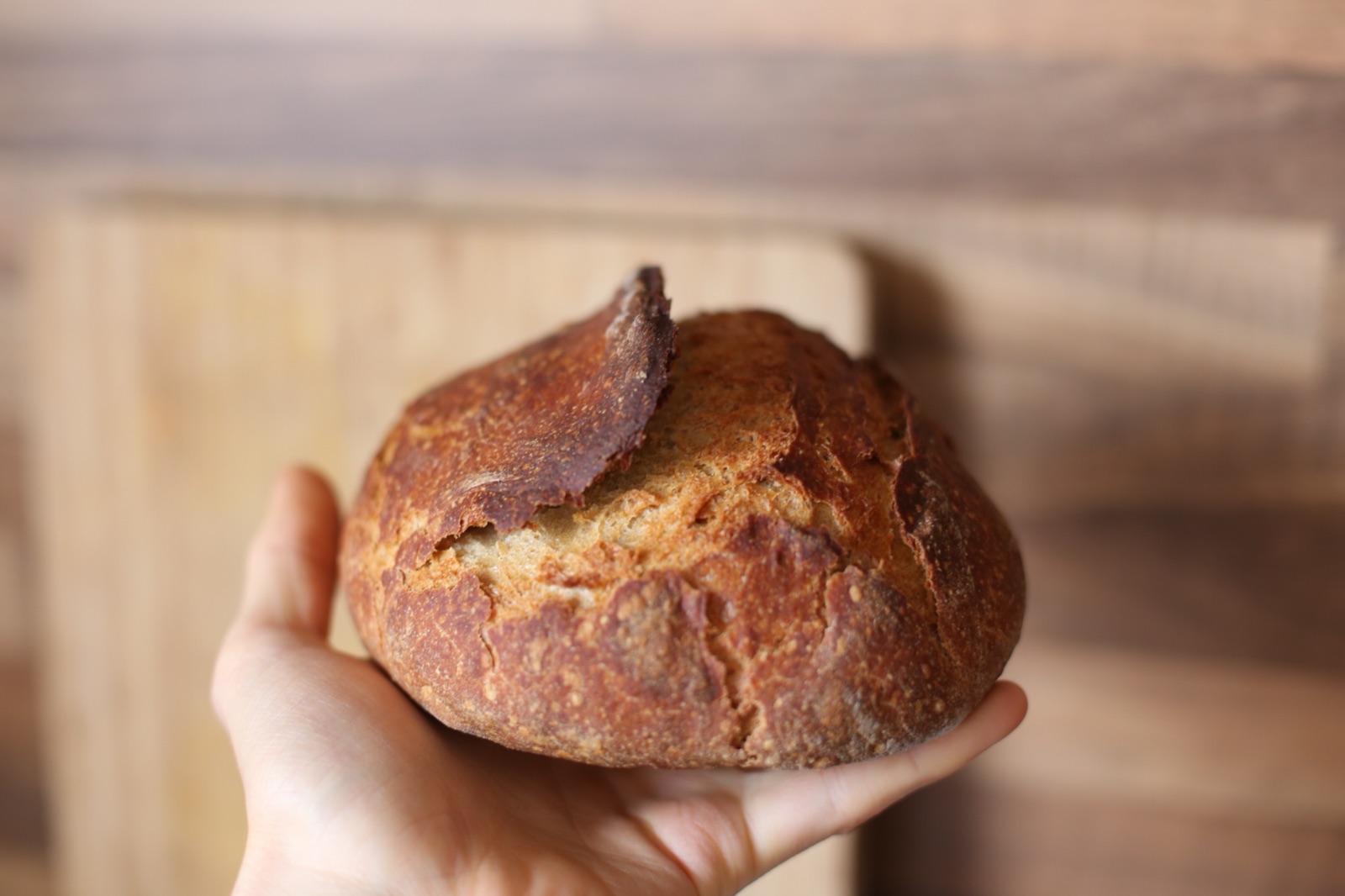 A crusty sourdough loaf held up in one hand